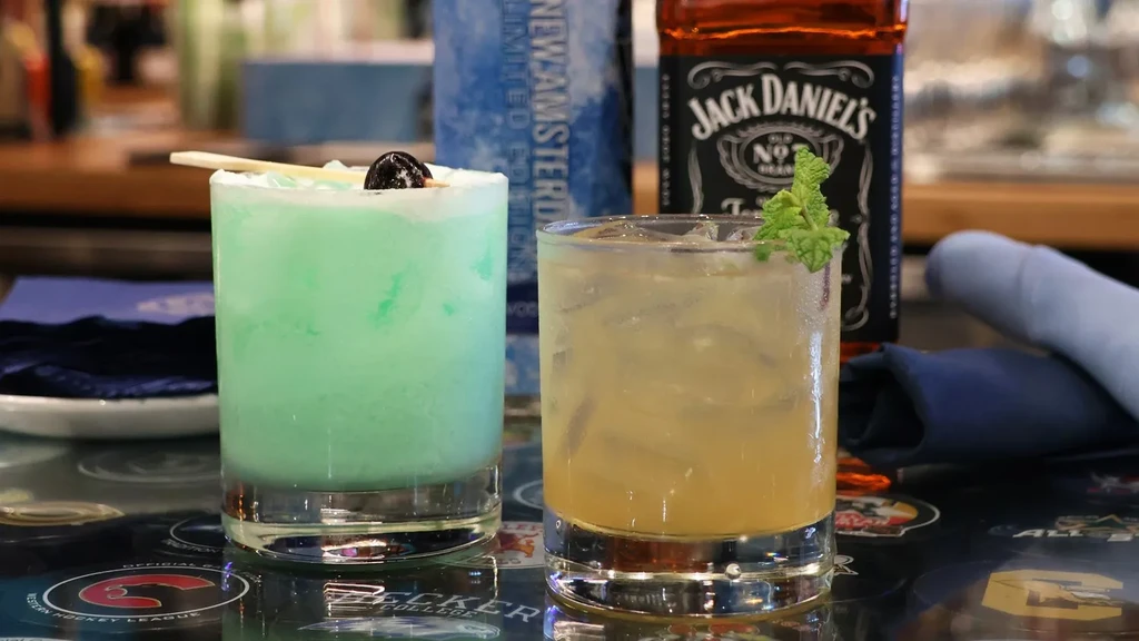 Two cocktails: one green with a cherry, one amber with mint.