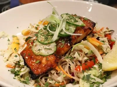 Glazed grilled salmon, cucumber, and scallions on a noodle salad with lemon.