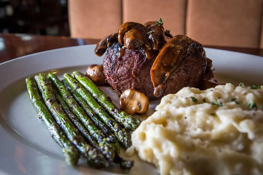 Gourmet steak with mushroom sauce, asparagus, and mashed potatoes.