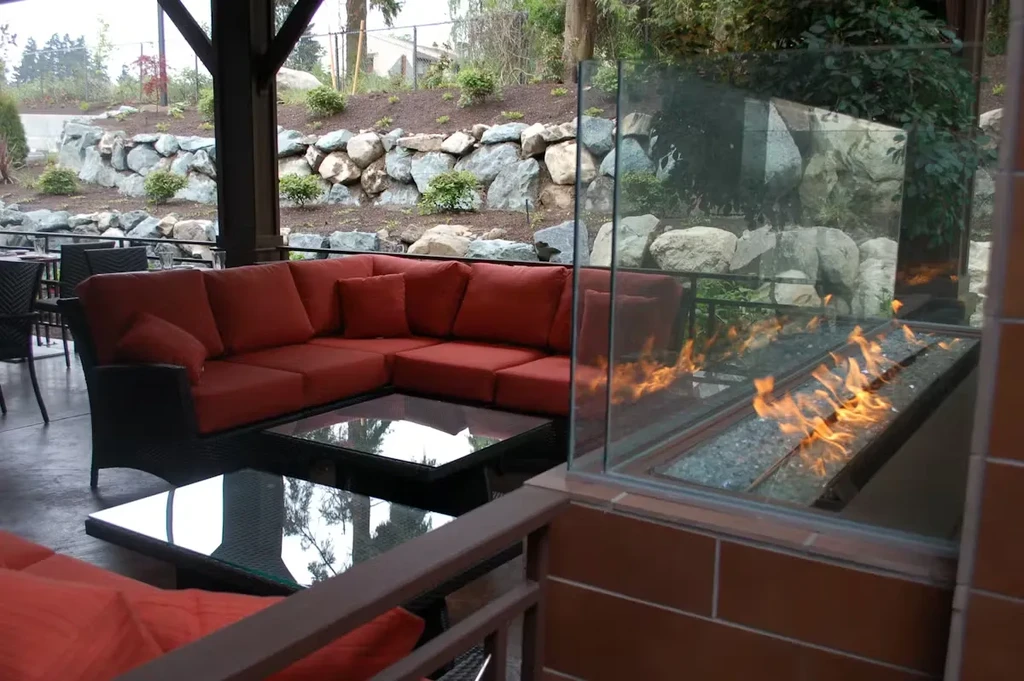 Modern outdoor lounge with red sofa and glowing gas fire pit.