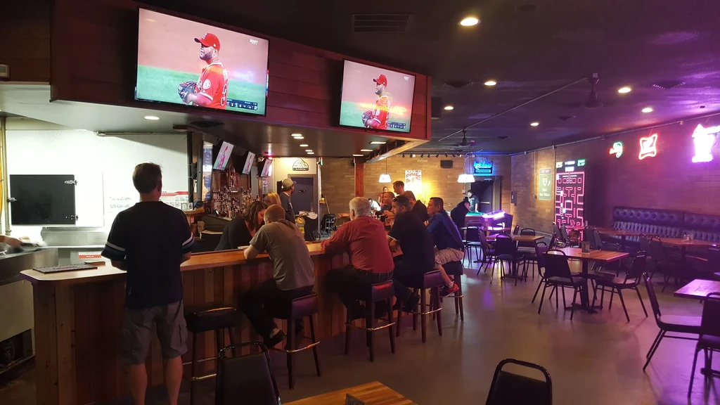 Patrons watch baseball on TV in a lively sports bar.