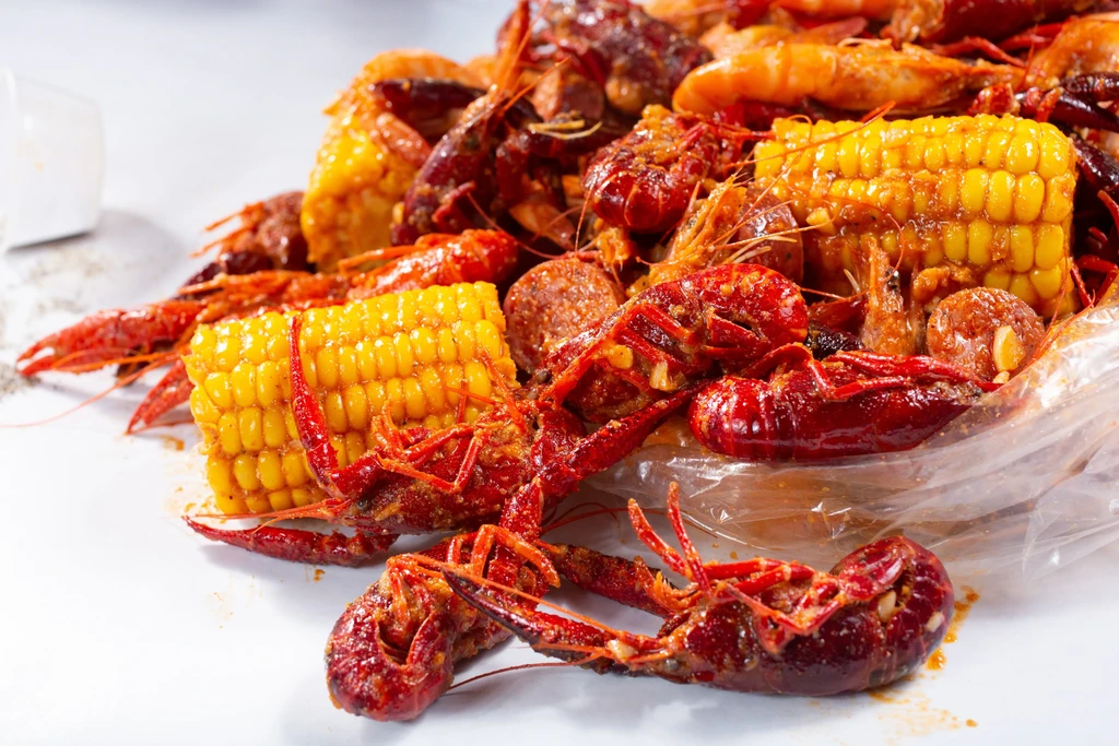 Seasoned crawfish, corn, and sausage seafood boil served on paper.