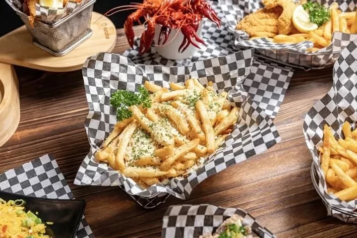 Rustic table with baskets of cheese fries, fried fish, and crawfish.