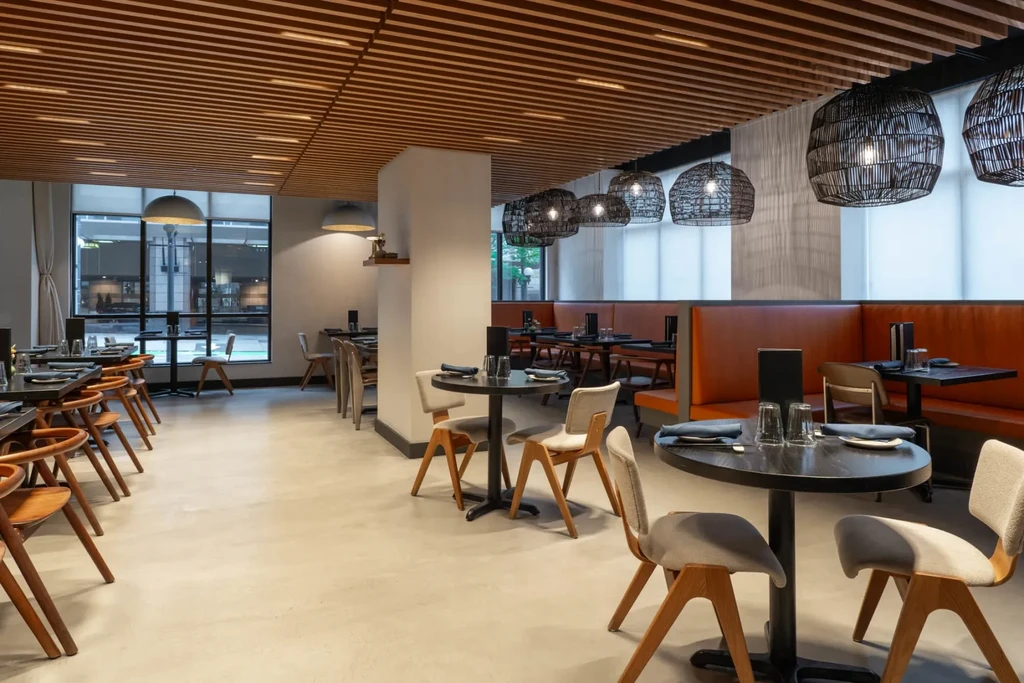 Modern restaurant interior with diverse seating and slatted wooden ceiling.