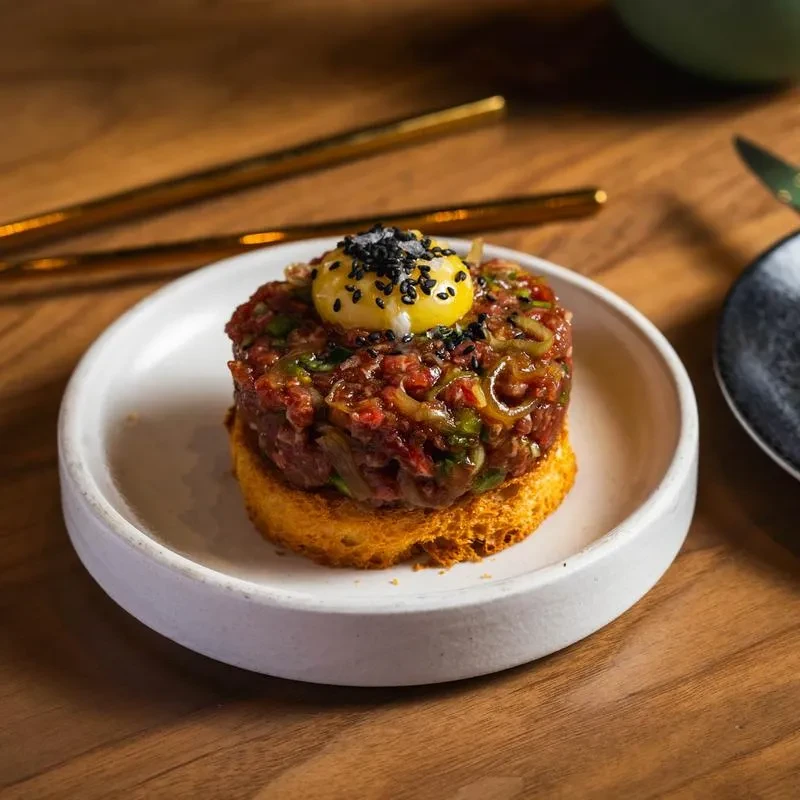 Close-up: Steak tartare on crostini with quail egg yolk and sesame seeds.