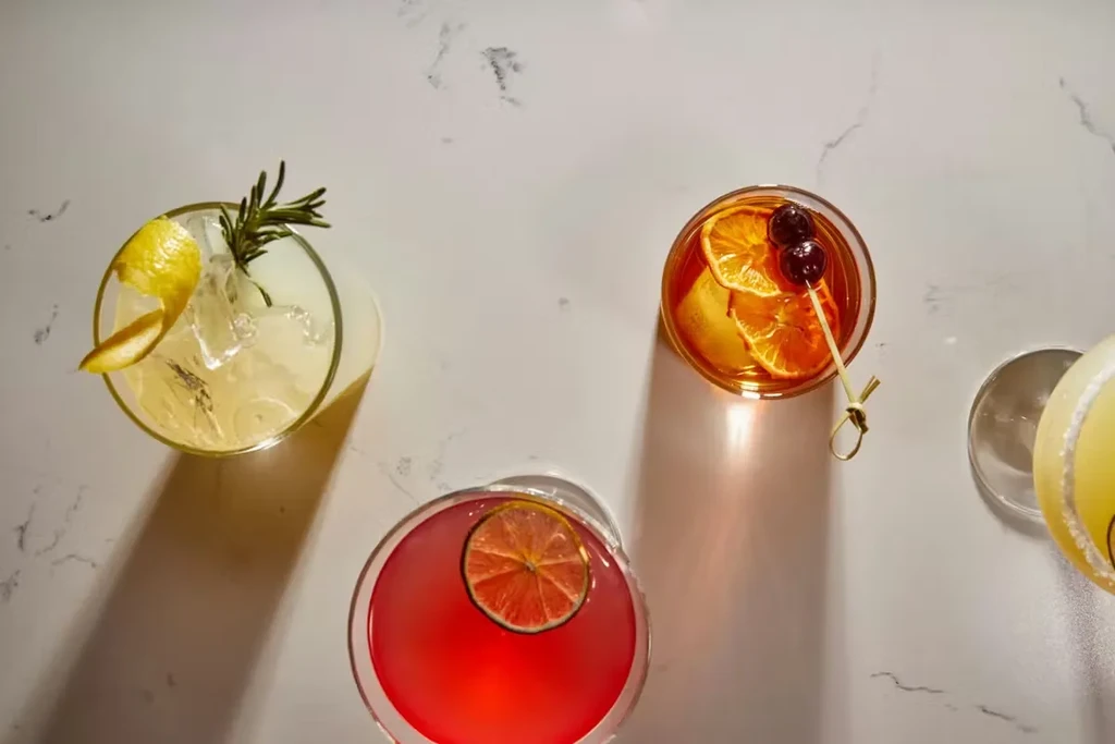 Four distinct cocktails with diverse garnishes on a veined surface.