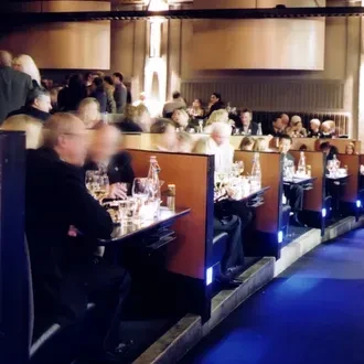 Upscale restaurant interior with bustling diners under warm and blue lights.