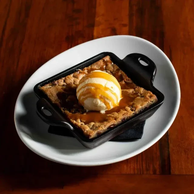 Skillet dessert with melting vanilla ice cream and caramel drizzle.