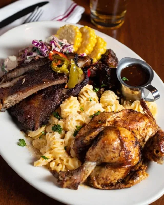 Platter with barbecued ribs, whole chicken, mac and cheese, corn, coleslaw.