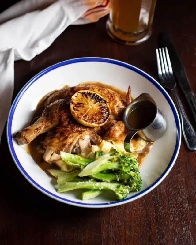Roasted chicken, mashed potatoes, and green vegetables with gravy.