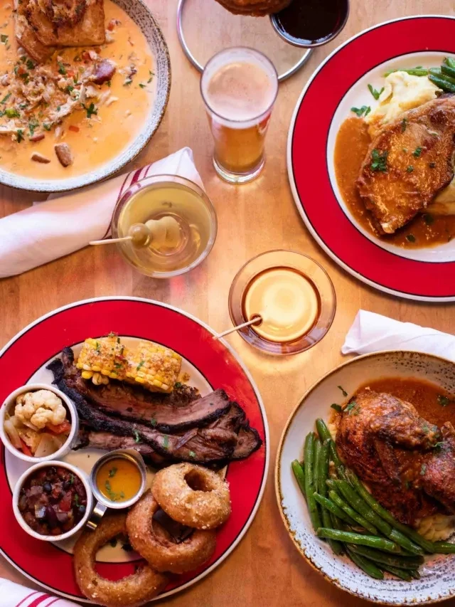 Overhead: Wooden table laden with diverse, hearty food and beverages.