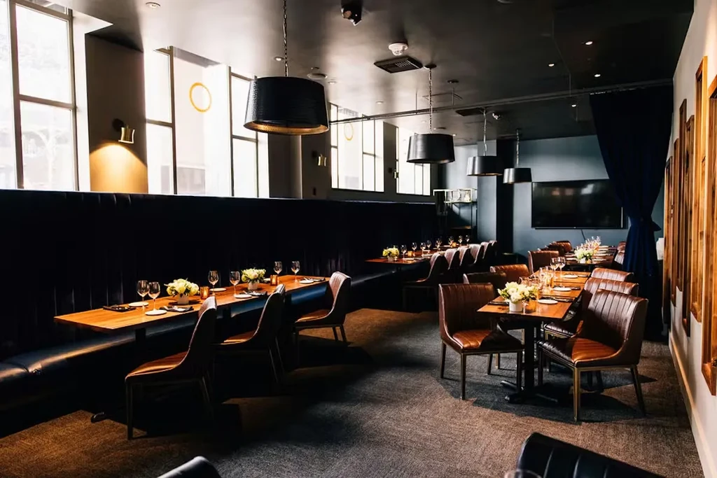 Vacant upscale dining room with navy booths, dark tables, set for service.