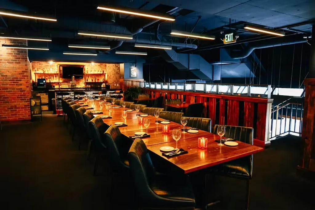 Empty restaurant interior with long set wooden table and bar.