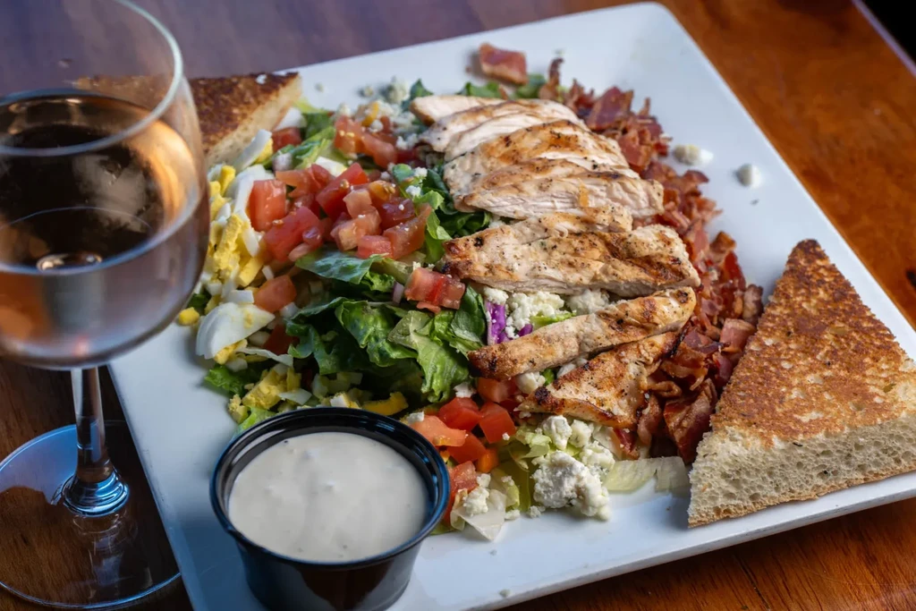 Cobb salad with grilled chicken, bacon, eggs, blue cheese, and dressing.