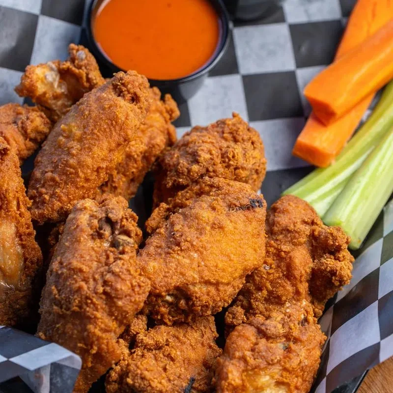 Crispy fried chicken wings, orange dipping sauce, carrots, and celery.