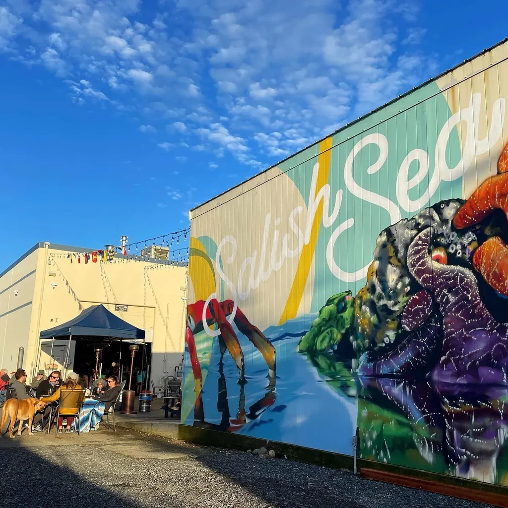Sunny outdoor restaurant patio next to a Salish Sea marine life mural.