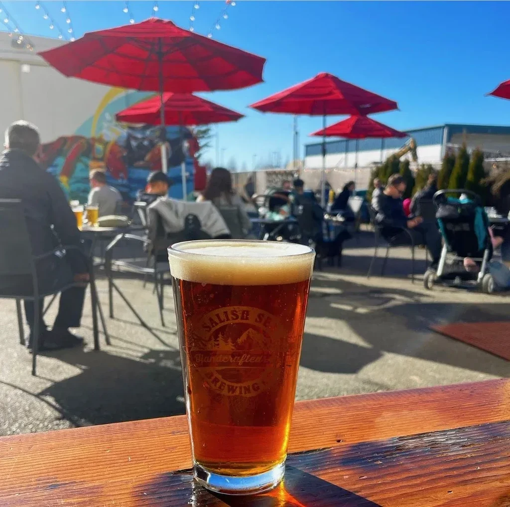 Pint of Salish Sea amber beer on a sunny outdoor patio.