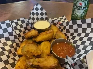 Basket of fried appetizers with two dipping sauces and a Heineken bottle.
