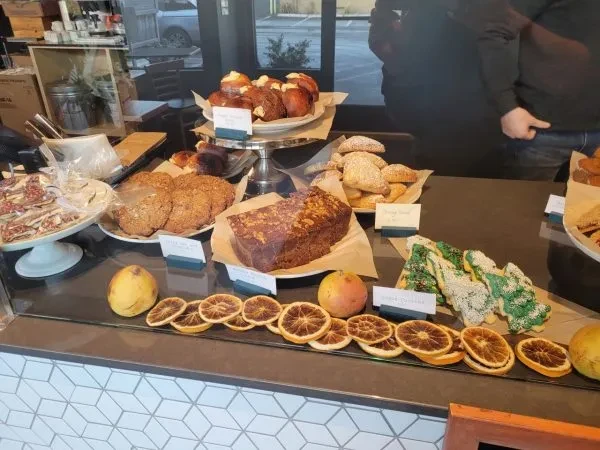 Counter display of diverse baked goods, pastries, and festive cookies.