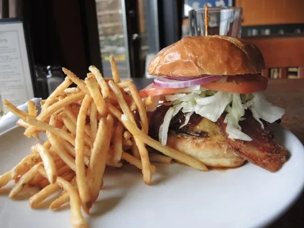 Gourmet bacon cheeseburger with tomato and a large side of fries.