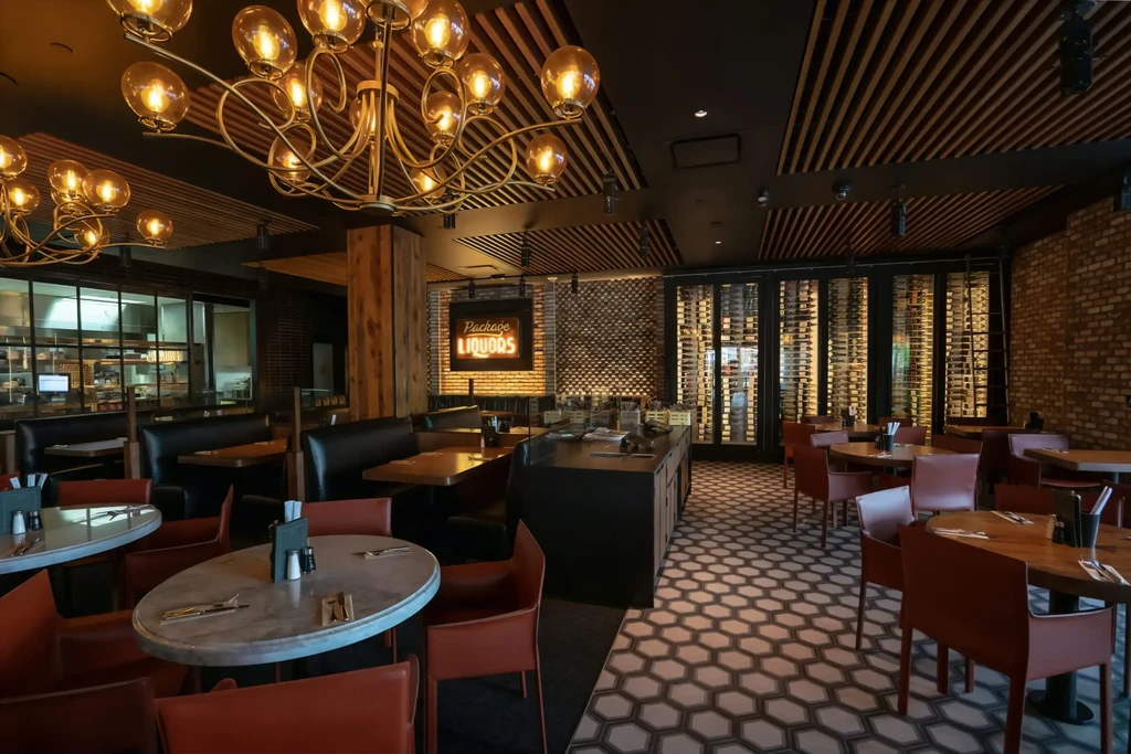 Modern industrial restaurant interior with exposed brick, ornate chandeliers, wine cellar.