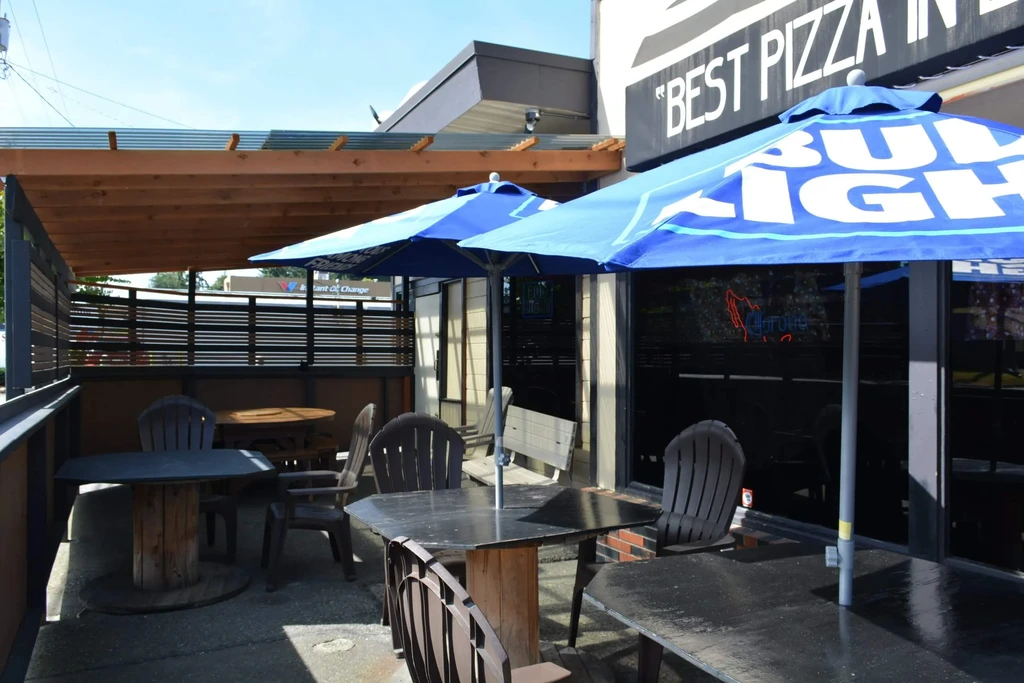 Empty outdoor restaurant patio with shaded seating and Bud Light umbrellas.
