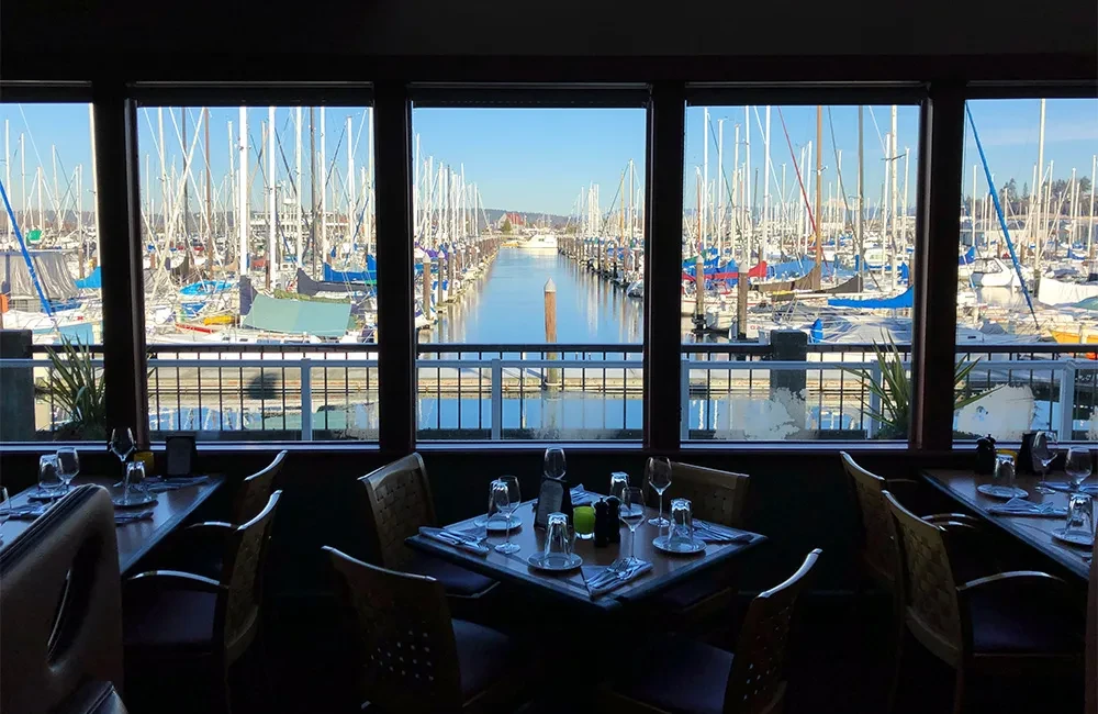 Restaurant interior overlooks a marina filled with sailboats and yachts.