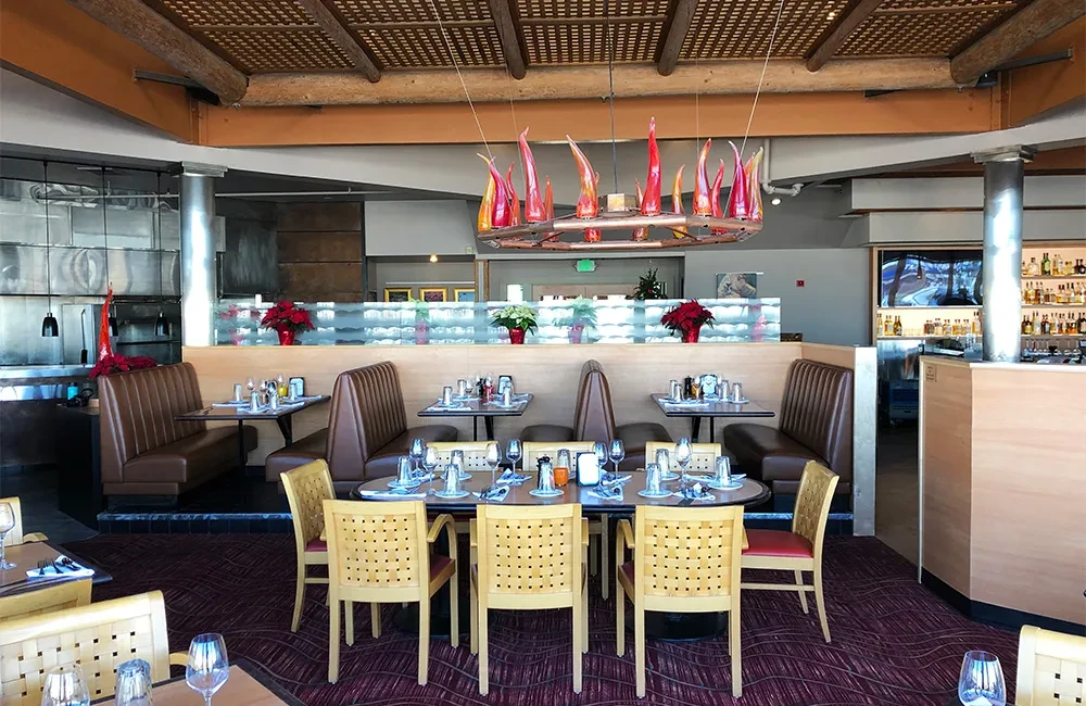 Empty, elegant restaurant dining area with set tables and flame-like chandelier.