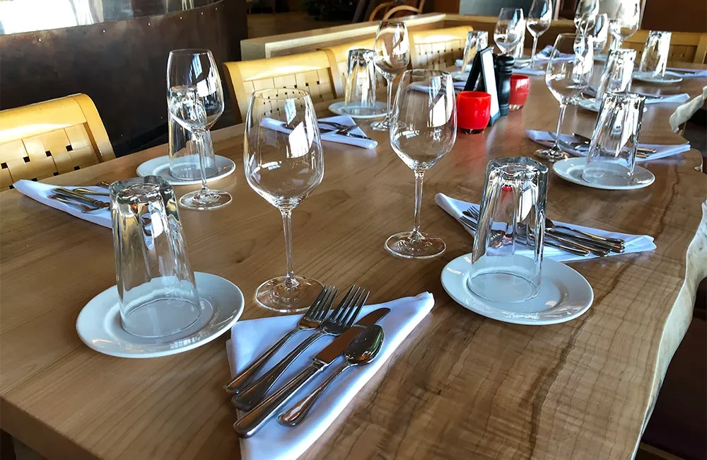 Live edge dining table set with plates, cutlery, and wine glasses.