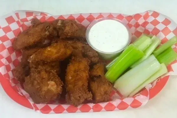 Basket of fried chicken wings with dipping sauce and celery sticks.