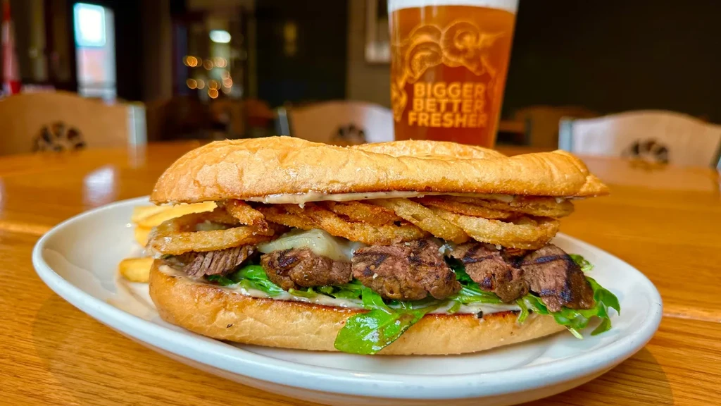 Steak sandwich, melted cheese, arugula, fried onions, fries, beer.