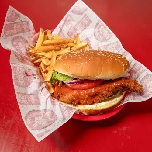 Spicy fried chicken sandwich and fries in a red basket.