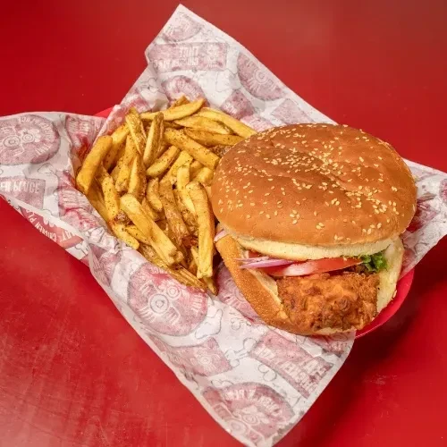 Fried chicken sandwich and seasoned fries in a red basket.