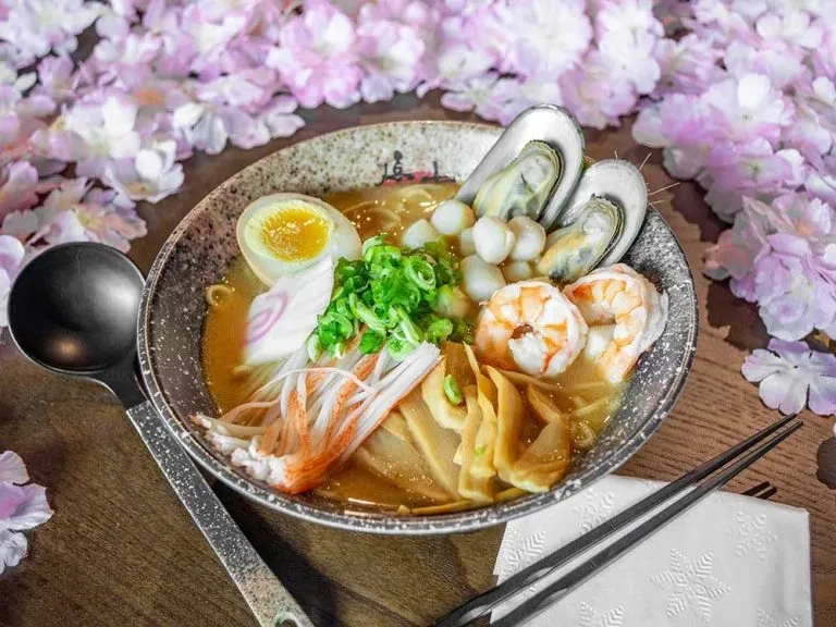 Golden-brown ramen with mussels, scallops, shrimp, egg, Narutomaki.