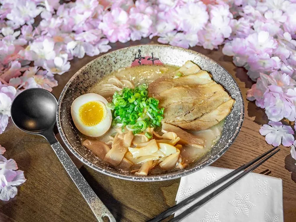 Overhead shot of ramen with pork, egg, green onions, and sakura.