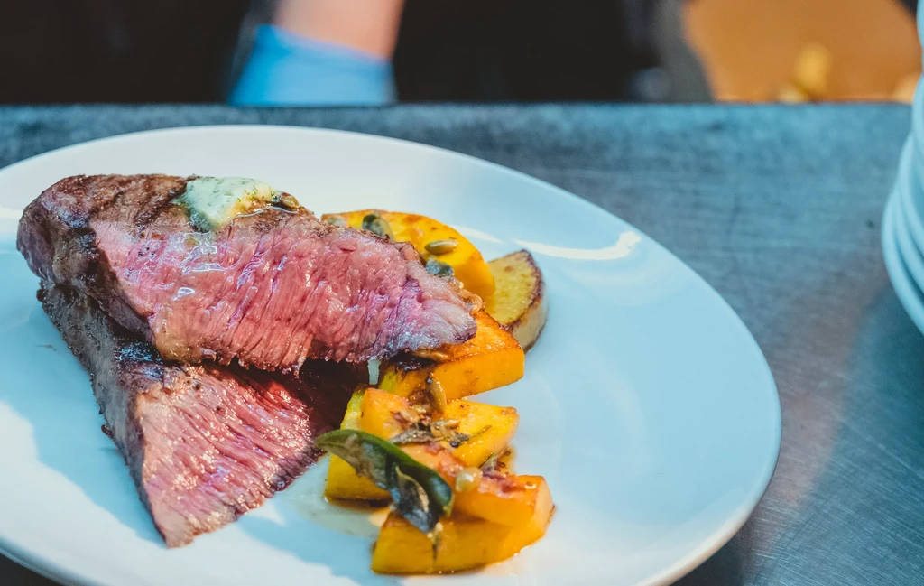 Medium-rare grilled steak with melting herb butter and roasted vegetables.