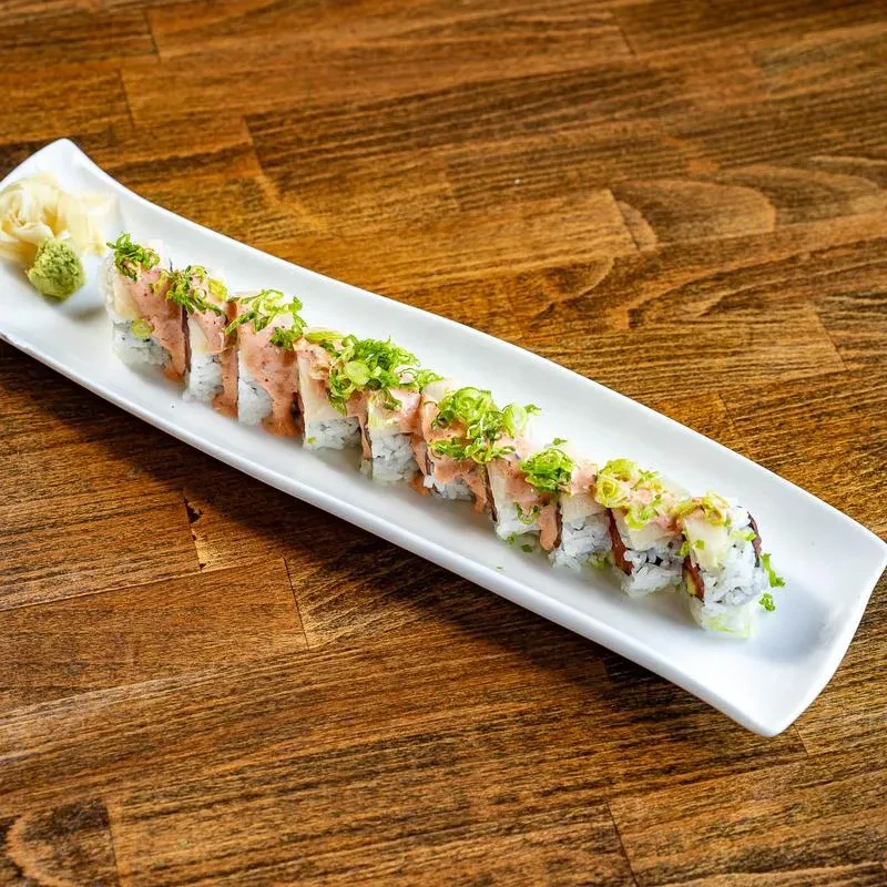 Platter of inside-out sushi, fish, green onions, sauce, ginger, and wasabi.
