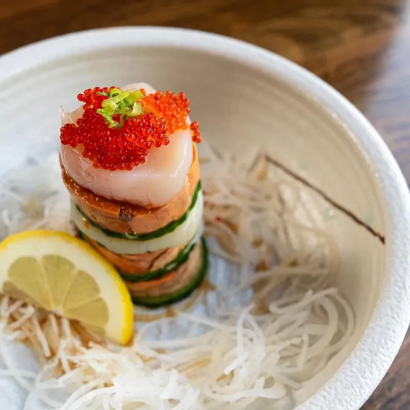 Japanese seafood tower with layered fish, caviar, and lemon.