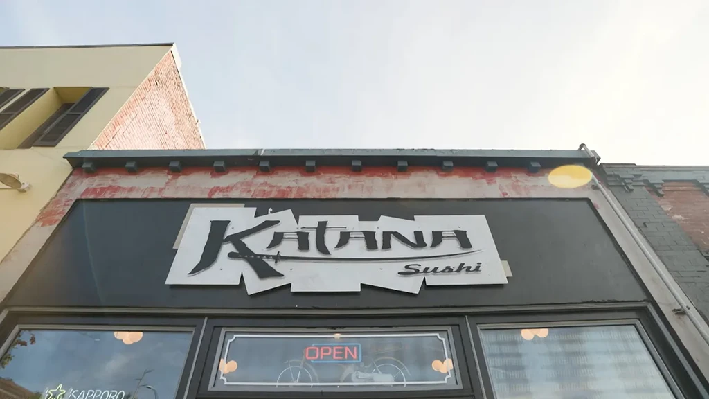 Katana Sushi sign on a building with a sword design.