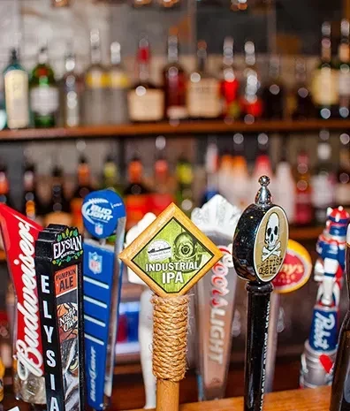 Close-up of diverse beer tap handles on a well-stocked bar.