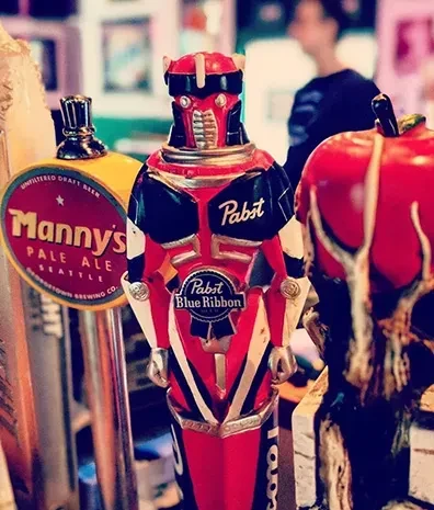 Close-up of decorative beer tap handles, featuring a robot Pabst.