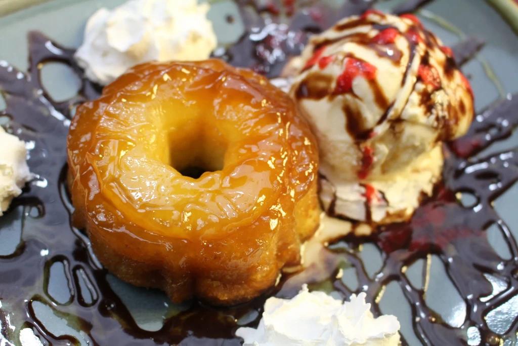 Golden ring dessert with vanilla ice cream, chocolate, and red sauce.