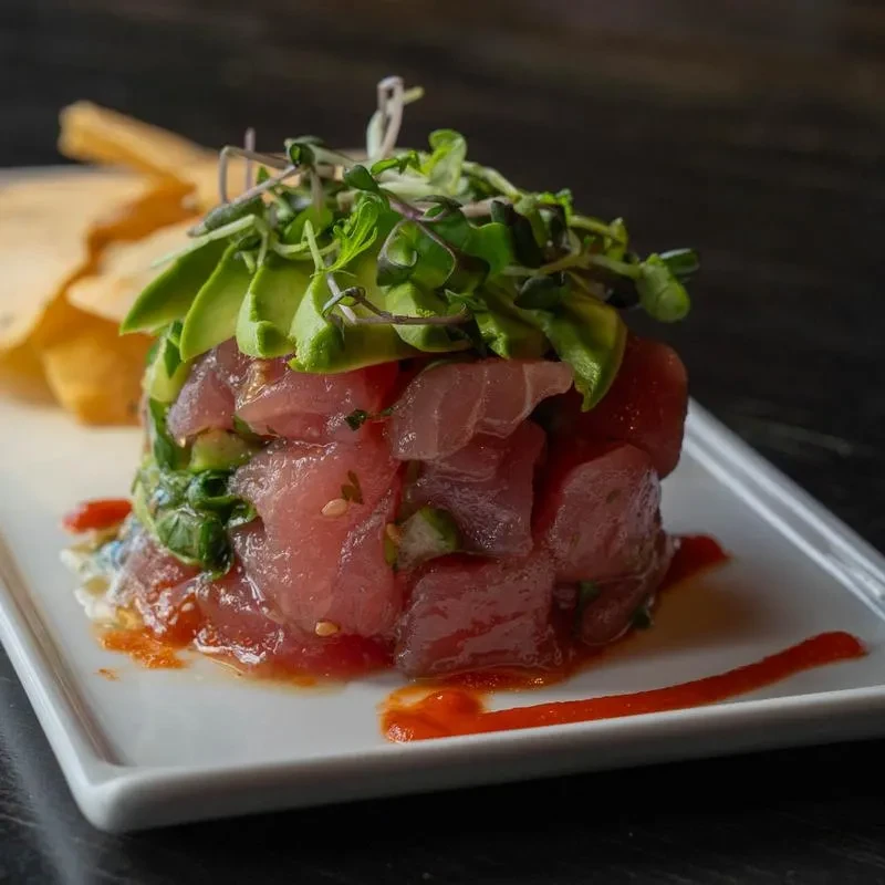 Tuna tartare with avocado, microgreens, red sauce, and crisps.