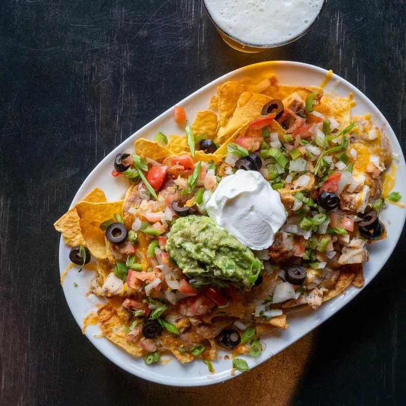 Loaded nachos with melted cheese, chicken, guacamole, and sour cream.