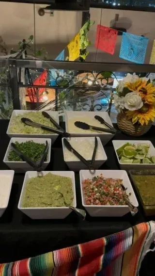 Festive Mexican taco buffet with fresh toppings, guacamole, and papel picado.