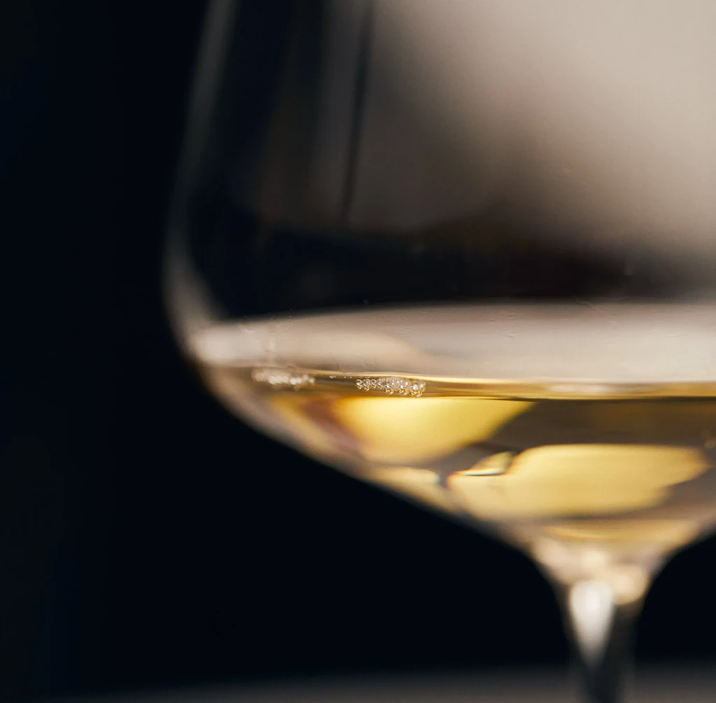 Close-up of a wine glass holding golden-yellow sparkling wine.