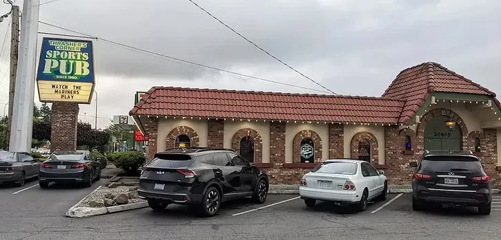 Thrasher's Corner Sports Pub building, red-tiled roof, prominent sign, parked cars.