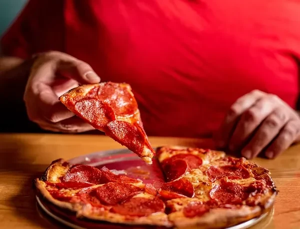 Close-up of a person lifting a slice of pepperoni pizza.