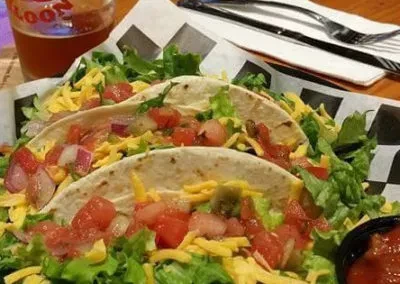 Three soft-shell tacos with meat, cheese, pico de gallo, and beer.