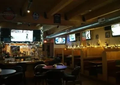 Dimly lit bar interior with taps, TVs showing sports, and booth seating.